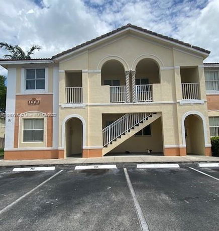 Front view of a two-story residential building with an exterior staircase and arches.