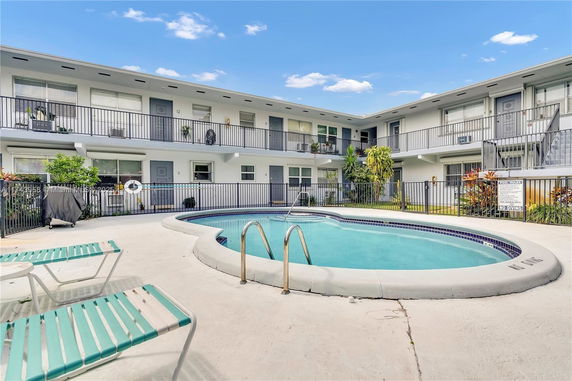 Outdoor swimming pool with a view of a two-story residential building.