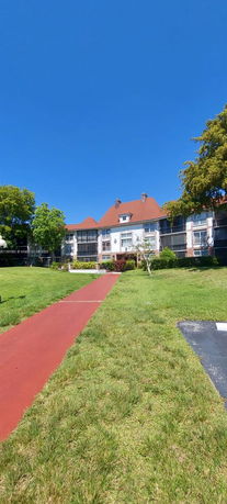 Front view of a multi-story building with a red roof and screened balconies.