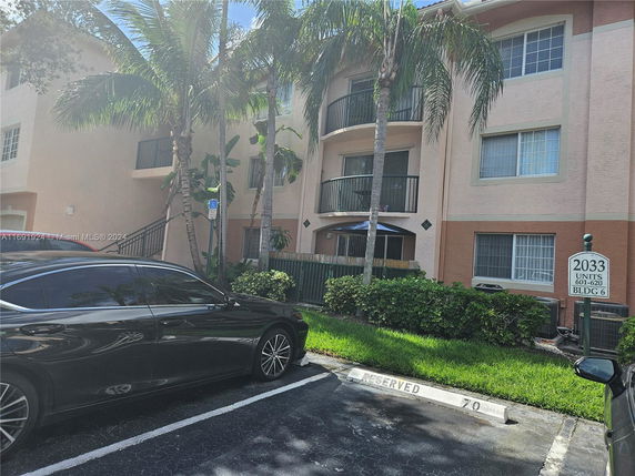 Front view of a multi-story residential building with balconies and parking area.
