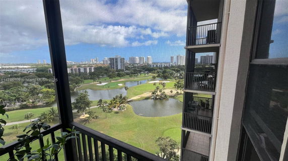 View from a balcony overlooking a landscaped area with a golf course and cityscape in the distance.