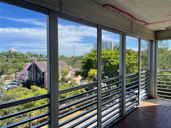 View from a balcony showing nearby buildings and trees.
