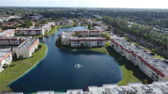 Panoramic view of residential buildings surrounding a water body with a fountain.