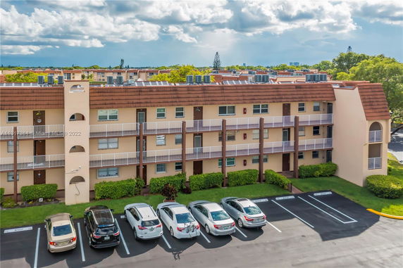 Front view of a multi-story residential building with parked cars.