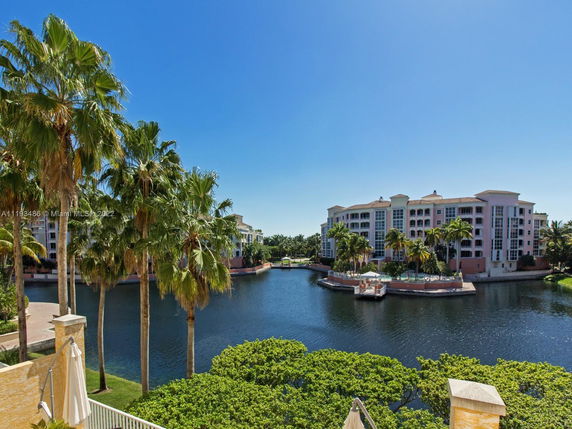 View of a waterfront building surrounded by palm trees.