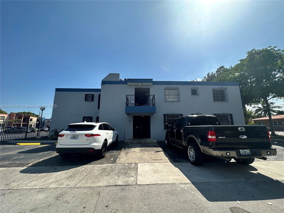 Front view of a two-story building with a parking area in front.