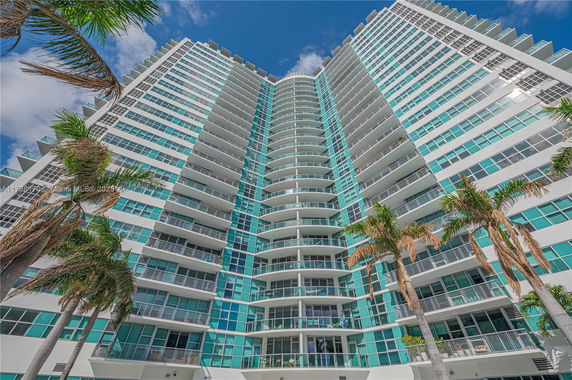 Front view of a high-rise building with multiple balconies and glass windows.