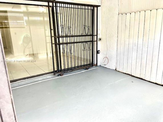 Outdoor area with a metal gate and a concrete floor adjacent to a building.