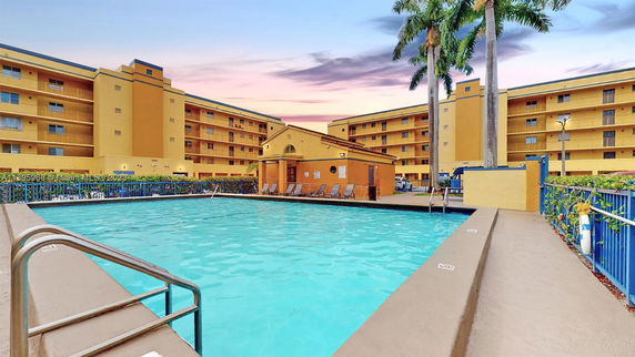 Outdoor swimming pool with surrounding multi-story apartment buildings.