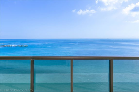 Panoramic view of the ocean from a balcony with glass railing.
