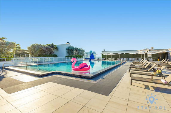 Rooftop swimming pool with lounge chairs and a flamingo float.