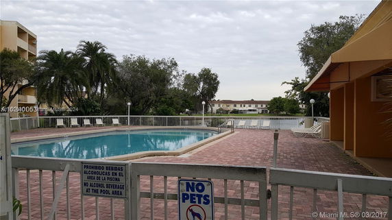 Outdoor view of a swimming pool with surrounding seating area and trees.