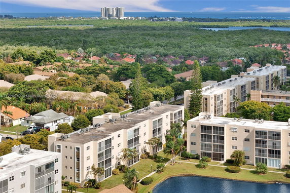 Panoramic view of residential buildings with surrounding greenery and a body of water.
