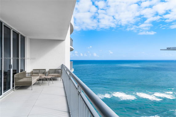 Balcony view overlooking the ocean with seating area.