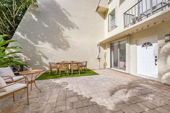 Outdoor patio area with a table, chairs, and white exterior wall of a house.