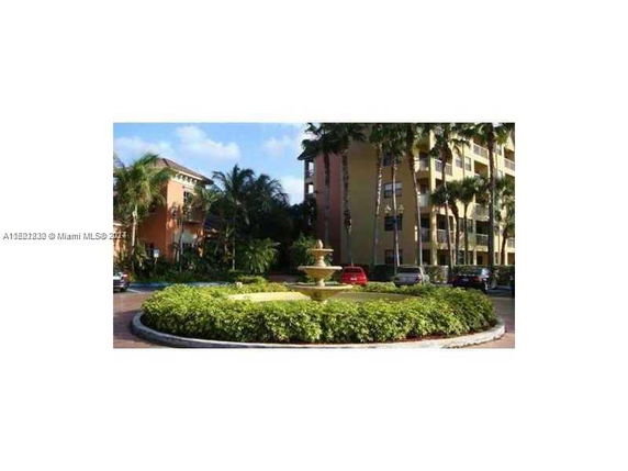 Front view of a multi-story residential building with a fountain in the foreground.
