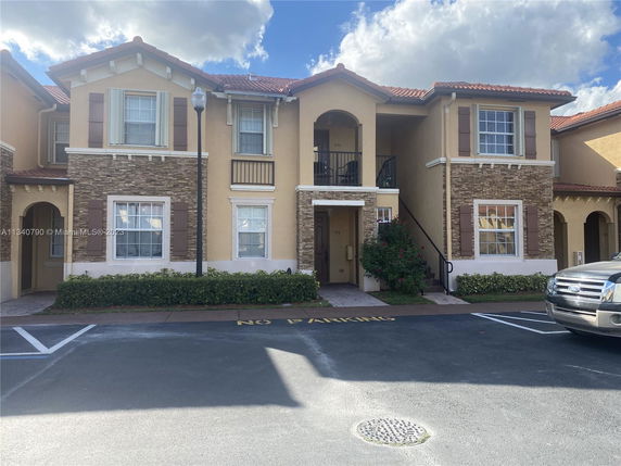 Front view of a two-story residential building with stone accents and brown shutters.