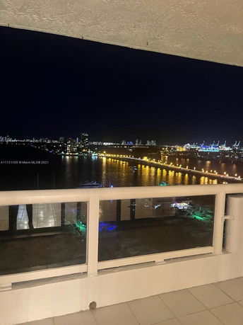 Panoramic view of a city skyline at night, seen from a balcony.