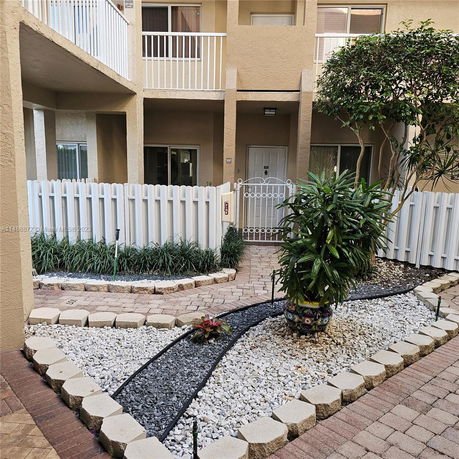 Front view of a two-story building with balconies and a garden in front.