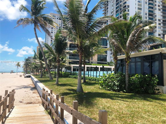 View of a beachfront building with palm trees lining the walkway.