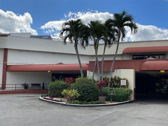Front view of a building with palm trees and covered entrance.