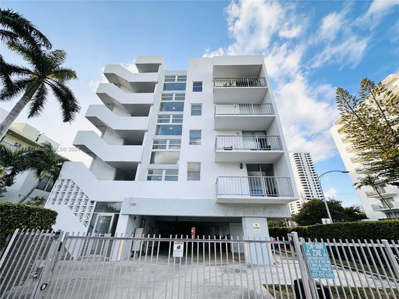 Front view of a multi-story residential building with balconies and gated entrance.