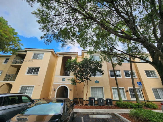 Front view of a three-story apartment building with beige exterior and multiple windows.