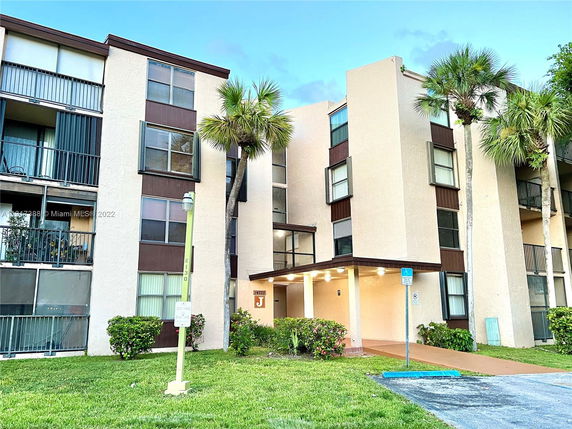 Front view of a multi-story residential building with balconies and a covered entrance.
