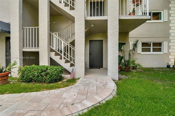 Exterior view of a building with stairs leading to upper levels and a pathway.