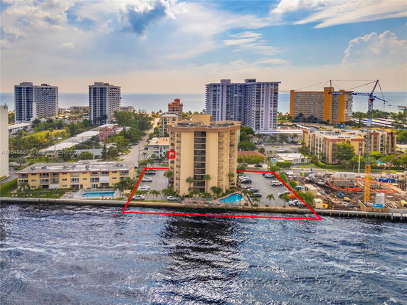Arial view of a mid-rise building complex near the waterfront with surrounding high-rise buildings.