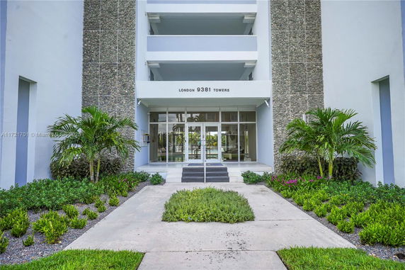Building entrance with steps leading to glass doors and stone facade.