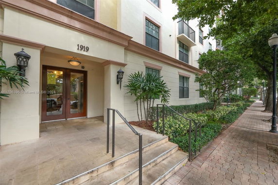 Front view of a multi-story building entrance with steps leading to double doors.
