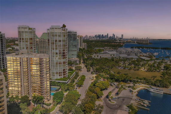Aerial view of high-rise buildings with a city skyline in the background near a waterfront area.