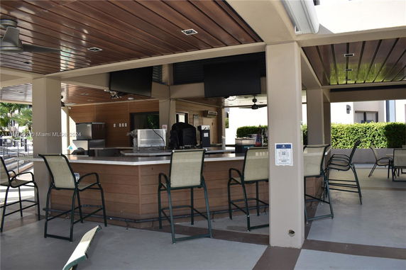 Outdoor club house area with bar seating and televisions.