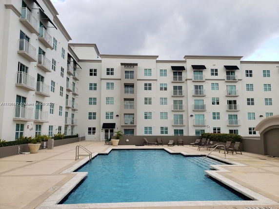 Front view of a multi-story residential building with a swimming pool in front.