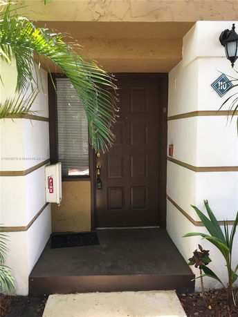 Front view of a building entrance with a brown door and a light fixture.