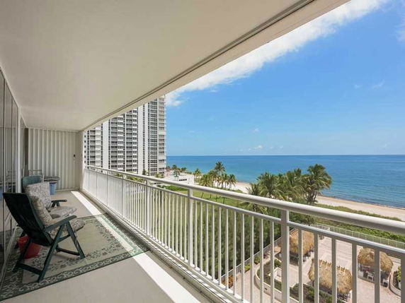View from a balcony overlooking the ocean and nearby buildings.