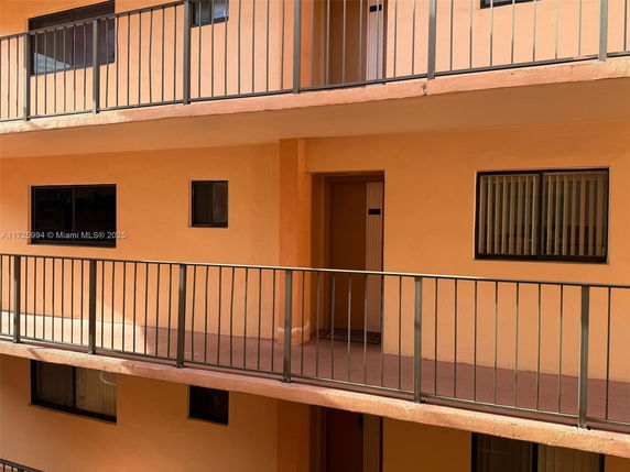 View of apartment balconies with orange exterior walls and metal railings.