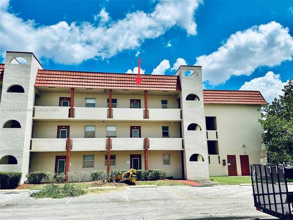 Front view of a multi-story building with balconies and a red tiled roof.