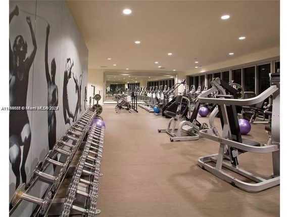 Interior view of a gym with workout equipment and mirrors.