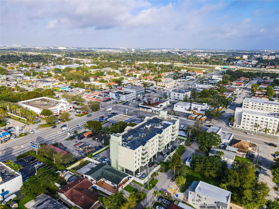 Aerial view of a cityscape with multiple buildings, roads, and vehicles.