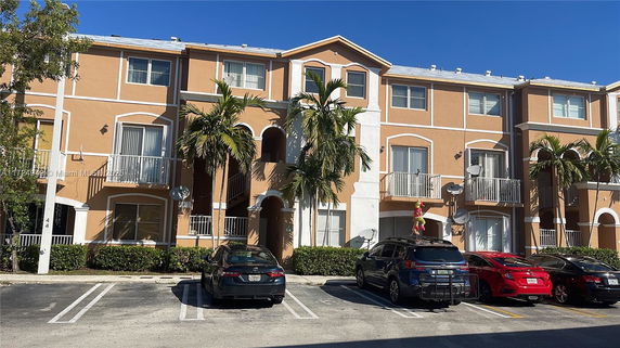 Front view of a three-story residential building with arched entrances and balconies.