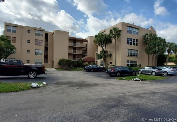 Front view of a multi-story apartment building with parking area.