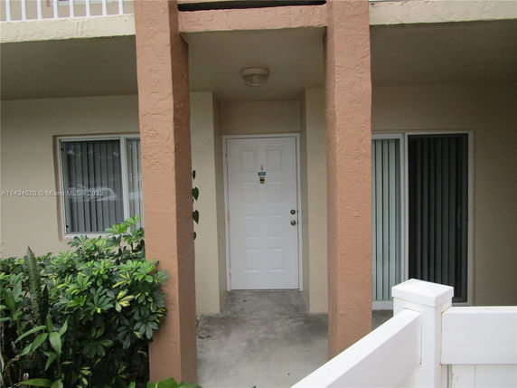 Front view of a house entrance with brown columns and a white door.