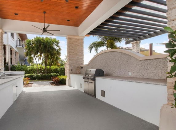 Outdoor covered patio area with a built-in grill and ceiling fan.