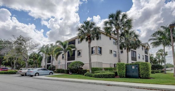 Front view of a multi-story apartment building with palm trees.