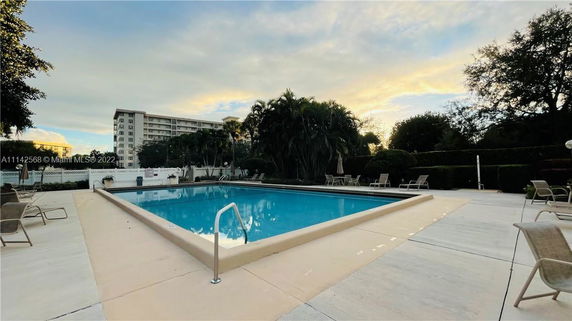 Outdoor swimming pool with surrounding deck chairs and lush greenery.