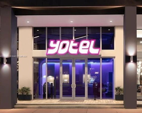 Front view of a modern building with a glass entrance and a large illuminated sign reading 'YOTEL'.