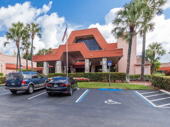Front view of a building with a distinctive triangular roof design and a parking area in front.