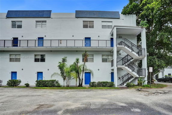 Front view of a multi-story building with blue doors and external staircases.